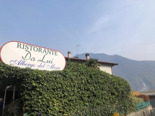 a sign on top of a ivy covered building at Albergo del mera-ristorante da Lui in Sorico