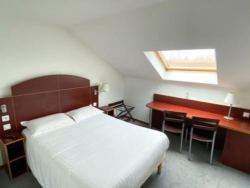 a bedroom with a bed and a desk and a window at Kyriad Direct Roanne Hôtel in Roanne