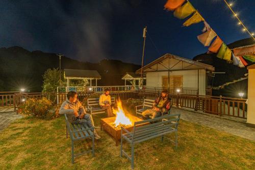 a group of people sitting around a fire pit at night at Zostel Plus Kareri in Dharamshala