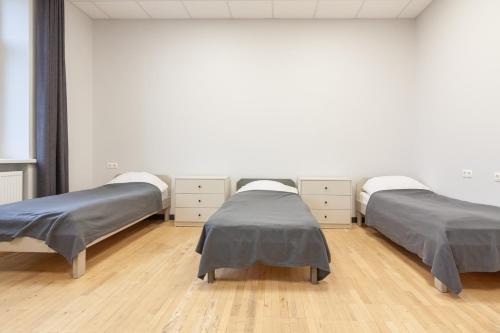 two beds in a white room with wooden floors at BAZZE in Klaipėda