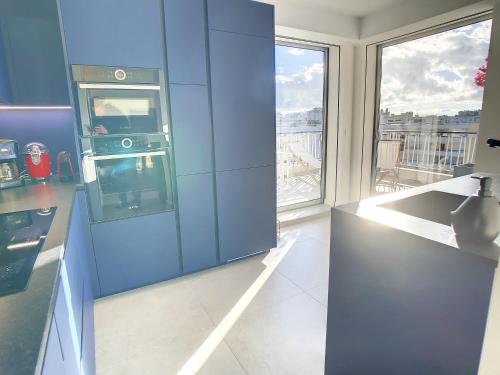 une cuisine avec des placards bleus et une grande fenêtre dans l'établissement Penthhouse 2 bedroom apartment 2 mins from the Croisette 335, à Cannes