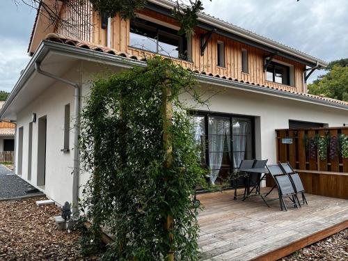 une maison avec une terrasse en bois devant elle dans l'établissement Flou de Pin, à Lège-Cap-Ferret