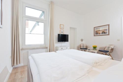 a white bedroom with a white bed and a window at Haus Menno Janssen - Doppelzimmer in Norderney