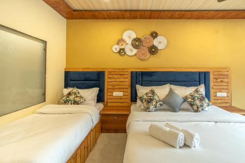 a bedroom with two beds and a clock on the wall at Zostel Plus Kareri in Dharamshala