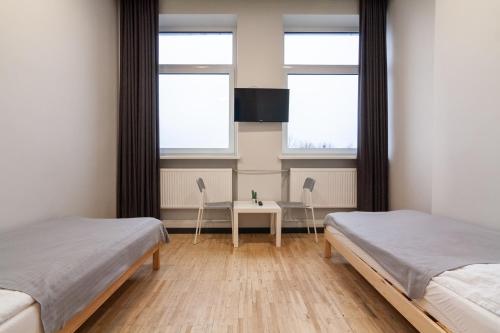 a bedroom with two beds and a table and two windows at BAZZE in Klaipėda
