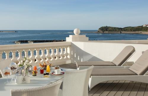 a table and chairs on a balcony with a view of the ocean at Grand Hôtel Thalasso & Spa in Saint-Jean-de-Luz
