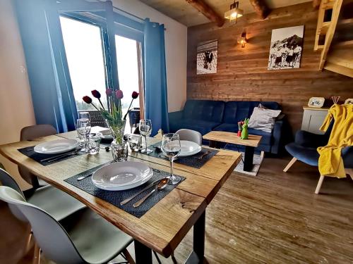 uma sala de jantar com uma mesa de madeira com pratos e copos de vinho em LassChata - Domki w górach z balią em Zakopane