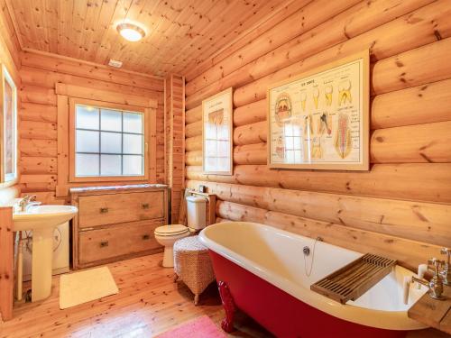 a log cabin bathroom with a tub and a sink at Grebe Lodge lodge 6 in Stratton Strawless