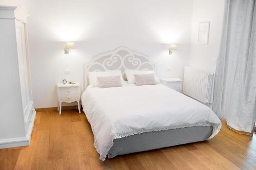 a white bedroom with a large bed with white sheets and pillows at Residenza Cantore in Verona