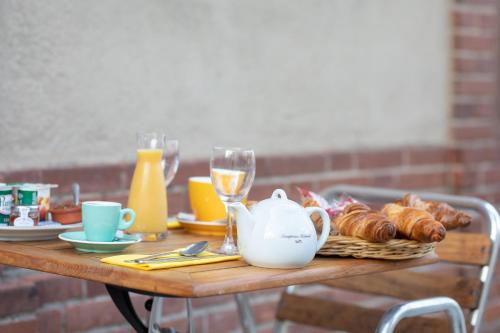 a table with croissants and a tea pot and glasses at Hôtel Brasserie du Parc in Albi