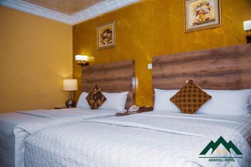 2 łóżka w pokoju hotelowym z żółtymi ścianami w obiekcie Ange Hill Hotel w Akrze
