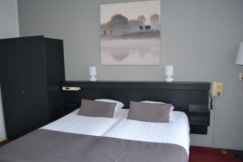een slaapkamer met een groot wit bed met 2 kussens bij Veluwe Hotel Stakenberg in Elspeet