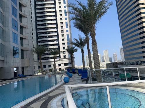 a large swimming pool with palm trees and buildings at Torch 77 in Dubai