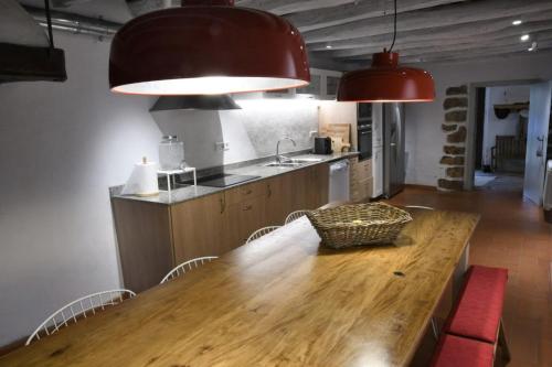 uma cozinha com uma mesa de madeira com cadeiras e 2 luzes em Masia Can Pitu em Santa Cristina d'Aro