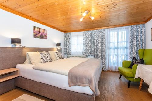 1 dormitorio con 1 cama grande y 1 silla verde en Ferienwohnung am Baby & Kinderbauerhof Stefflhof, en Saalfelden am Steinernen Meer