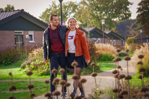 a man and a woman standing in a garden at Vakantiepark De Boshoek - Luxe Groepsverblijven op de Veluwe in Voorthuizen