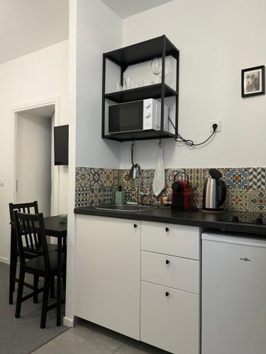 a kitchen with white cabinets and a table with a microwave at VILLA VLAS - Chambre d'Hôte - Limoges in Limoges