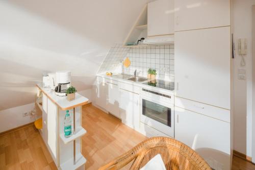 eine Küche mit weißen Geräten und Holzböden in der Unterkunft Haus Dwarslooper - Wohnung Lüntje in Norderney