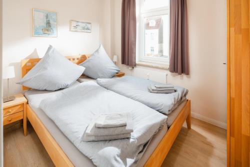 - 2 lits dans une chambre avec des serviettes dans l'établissement Strandloge, à Norderney
