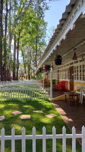 a white fence in front of a yard with a picnic table at Citadel Resort in Panchgani
