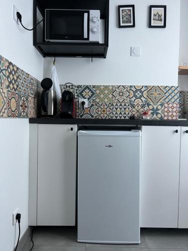 a kitchen with white cabinets and a microwave at VILLA VLAS - Chambre d'Hôte - Limoges in Limoges