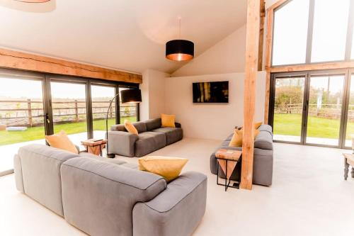 a living room with two couches and a tv at Beautiful Barn Conversion Close To The Broads in Dilham