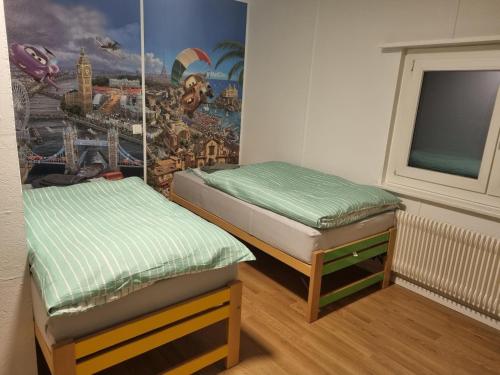 two beds in a room with a mural on the wall at 24-7 Rooms in Sennwald