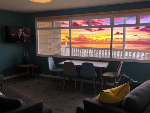a room with a table and a window with a sunset at Braddicks Holiday Centre in Westward Ho