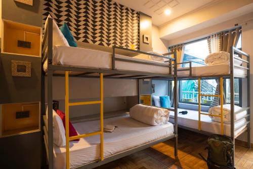 a room with three bunk beds and a window at Zostel McLeodganj in McLeod Ganj