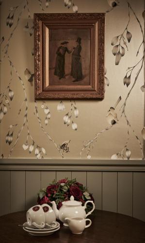 a table with two tea cups and a picture on the wall at Monkstadt 1745 Restaurant with Rooms in Portree
