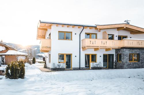 a house with a balcony in the snow at Tiroli in Westendorf
