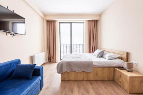 ein Schlafzimmer mit einem Bett und einer blauen Couch in der Unterkunft New Gudauri, Alpic - Ski Resort at Your Doorstep - Stylish & Comfy Ski Apartment with ski-depot and Stunning Mountain Views in Gudauri