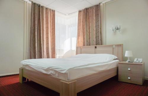 1 dormitorio con 1 cama y una ventana con cortinas en City Hotel, en Yekaterinburg