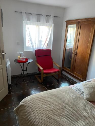 een slaapkamer met een rode stoel en een tafel bij Propriétaire privé in Carcassonne