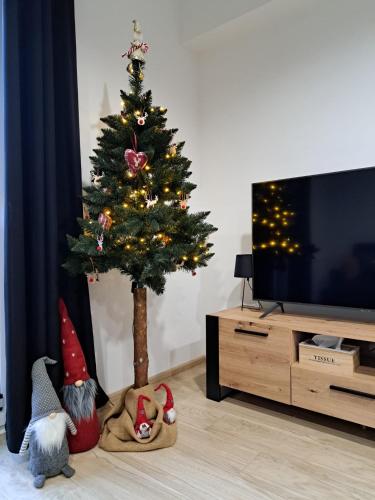 a christmas tree with decorations in a living room at ŁośHouse in Bytów