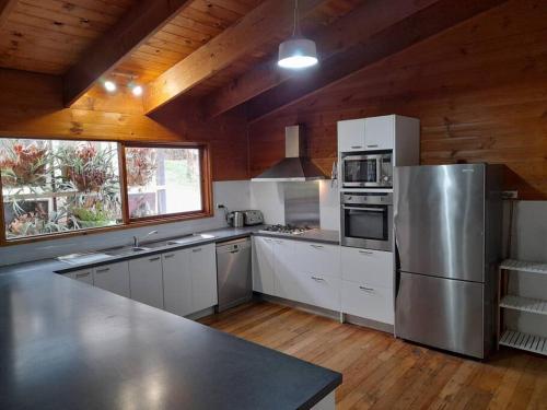 a kitchen with white cabinets and a stainless steel refrigerator at Bells Beach Family Retreat in Bellbrae