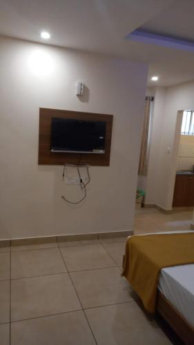 a room with a tv on a wall with a bed at Greenpark Residence in Mama