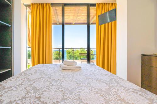 a bedroom with a bed with yellow curtains and a window at Kalma Villa Pente in Nea Moudania