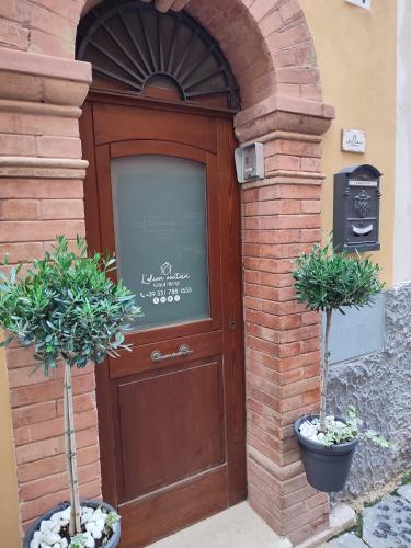 uma porta castanha com dois vasos de plantas à frente em L'OLIVA CONTESA - alloggio turistico - la ROSSA em Gaeta