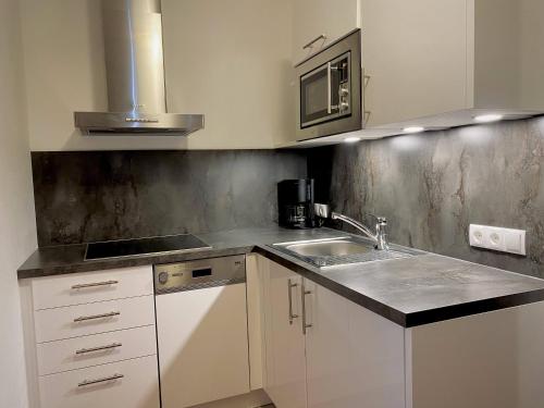 a kitchen with white cabinets and a sink at Hotel Garni Philipp in Serfaus