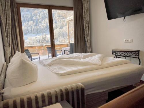 Bett in einem Zimmer mit einem großen Fenster in der Unterkunft Hotel Garni Philipp in Serfaus