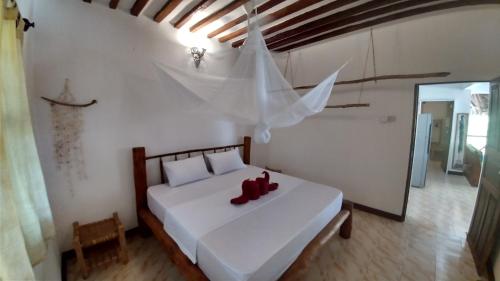 a bedroom with a white bed with red shoes on it at Wonderful Ocean Villa in Jambiani