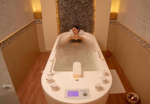 a woman is sitting in a bath tub at Royal Tulip Korbous Bay Thalasso & Springs in Qurbuş