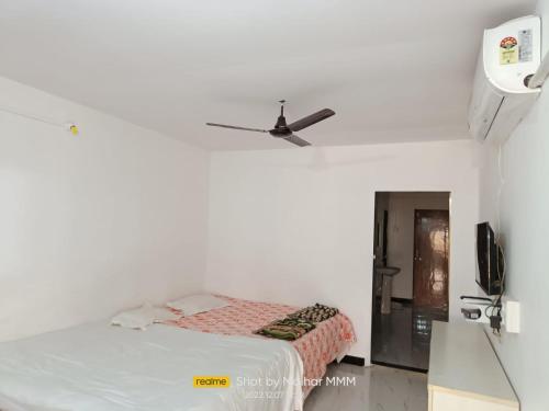 a white bedroom with a bed and a ceiling fan at Kulswami Cottage Alibag in Alibaug