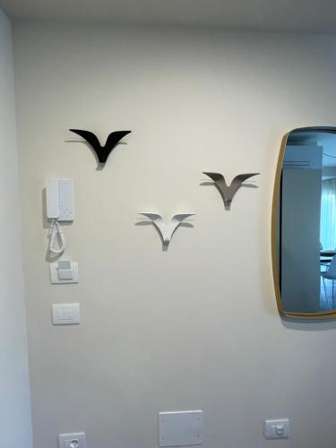a wall with birds on a wall with a tv at Lucia Holiday Apartments in Lazise
