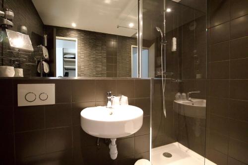 a bathroom with a sink and a glass shower at Appia La Fayette in Paris