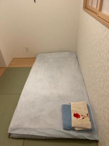 Una cama con colcha blanca y una toalla. en Bessalov Home Japanese style room en Tokio