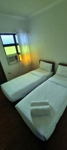 two beds in a room with a window at RedDoorz Plus at Balai Sofia Bed & Breakfast Batangas in Talisay
