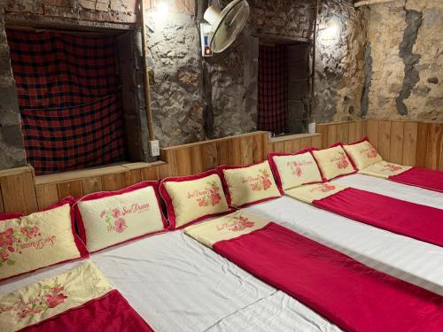 two beds with red and white pillows in a room at Trường Giang Homestay in Cao Bằng