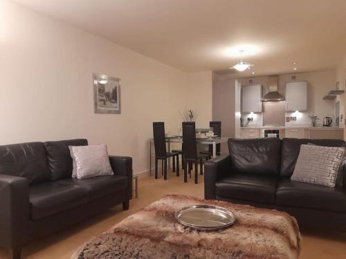 ein Wohnzimmer mit einem schwarzen Sofa und einem Tisch in der Unterkunft Centrally situated 1 bedroom apartment! in Birmingham